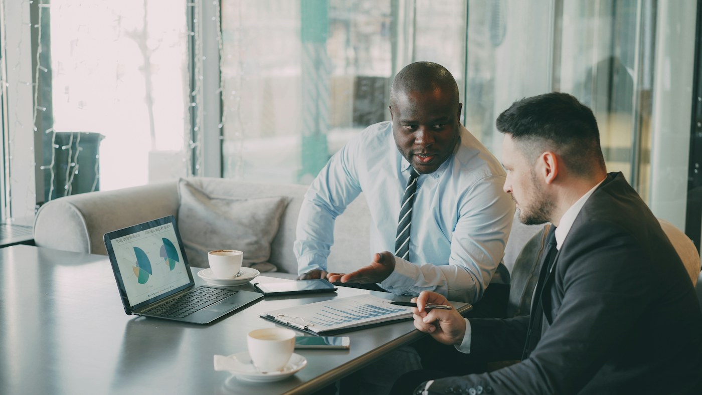 Business professionals reviewing charts on a laptop, representing CRM insights delivered through AI interfaces