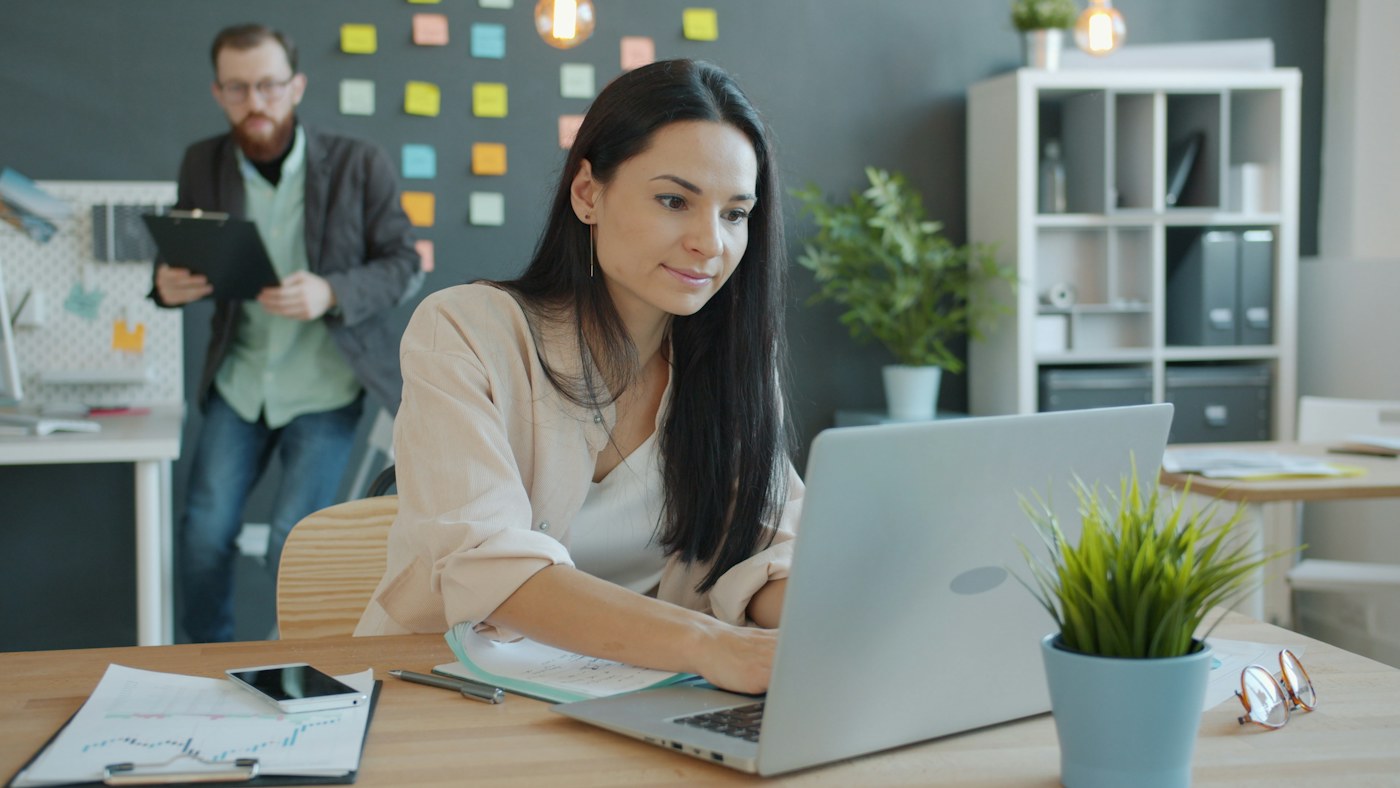 Colleagues discussing a document beside a laptop, representing human and AI agent collaboration