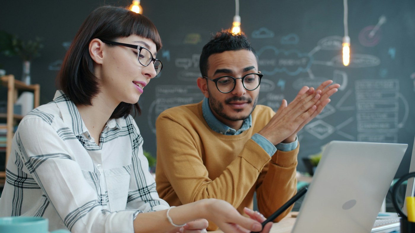 Coworkers discussing information on a laptop, illustrating collaborative AI-powered CRM workflows