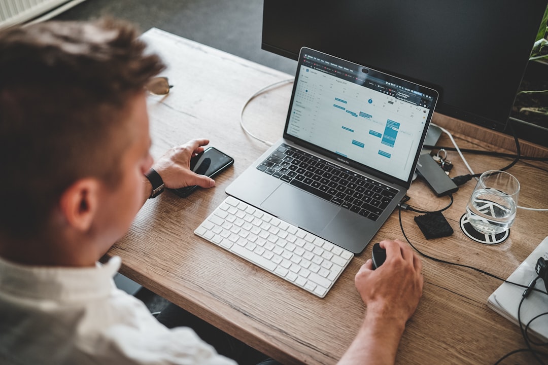 Professional using laptop and phone for connected business data analysis