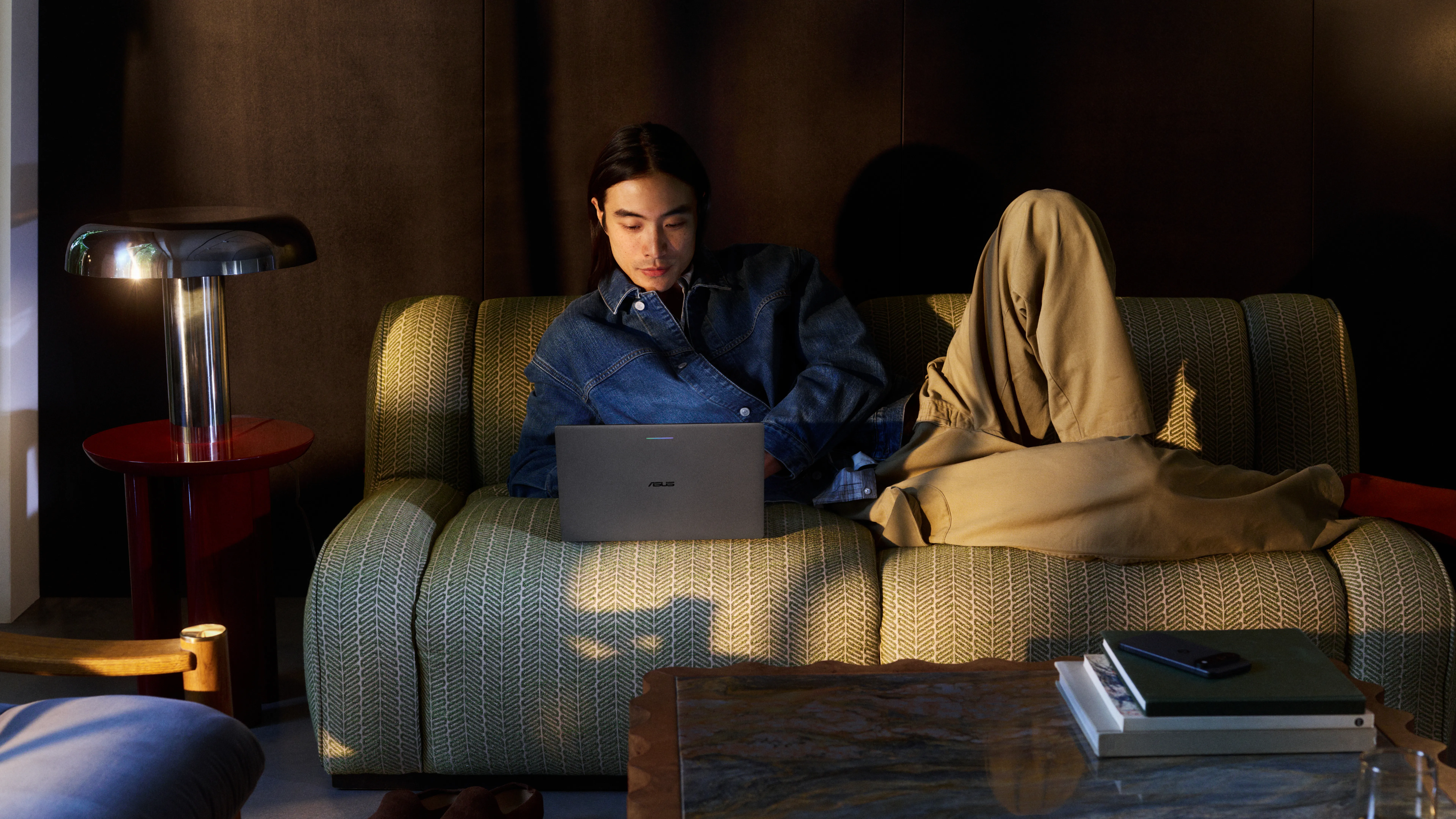 Person using an ASUS Googlebook laptop in a living room setting