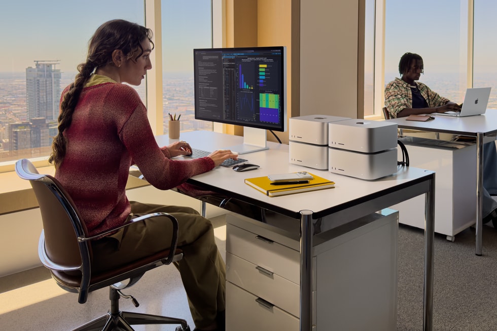 Professional workspace with four Mac Studio computers clustered beside a display