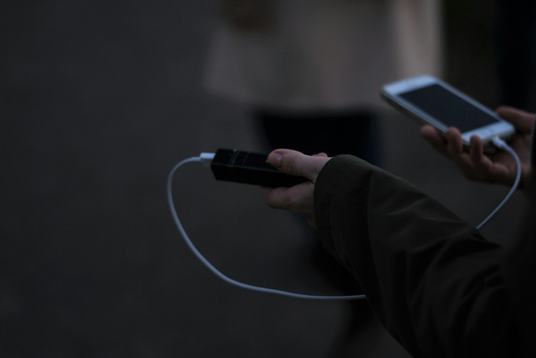 Person holding a smartphone and charging cable
