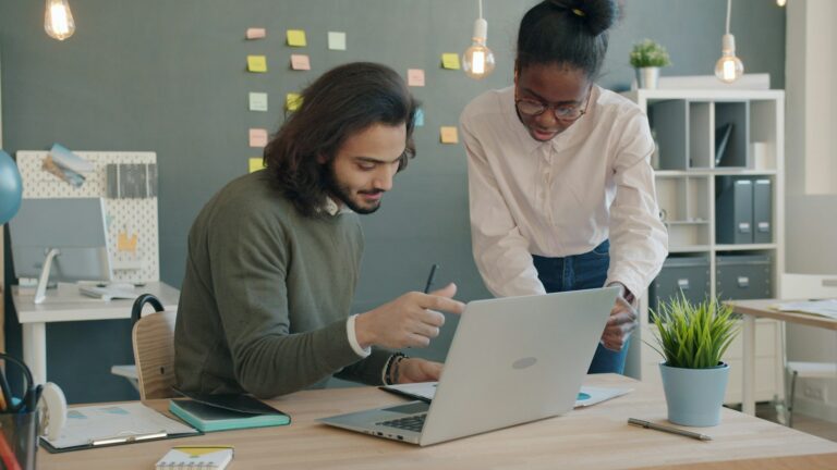 Two coworkers reviewing documents and a laptop, representing AIforce CRM collaboration
