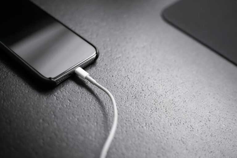 Smartphone connected to a charger on a desk