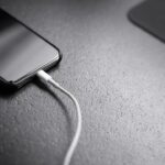 Smartphone connected to a charging cable on a desk
