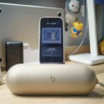 A smartphone charging on a desk with accessories, editorial photograph illustrating battery troubleshooting; not an iOS screenshot